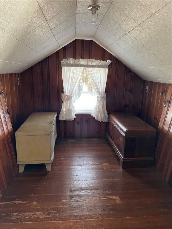 additional living space featuring wood walls, dark hardwood / wood-style flooring, and lofted ceiling