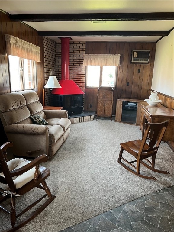 carpeted living room with beam ceiling, a wood stove, wooden walls, and a wall mounted air conditioner