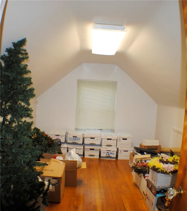 additional living space with wood-type flooring and vaulted ceiling