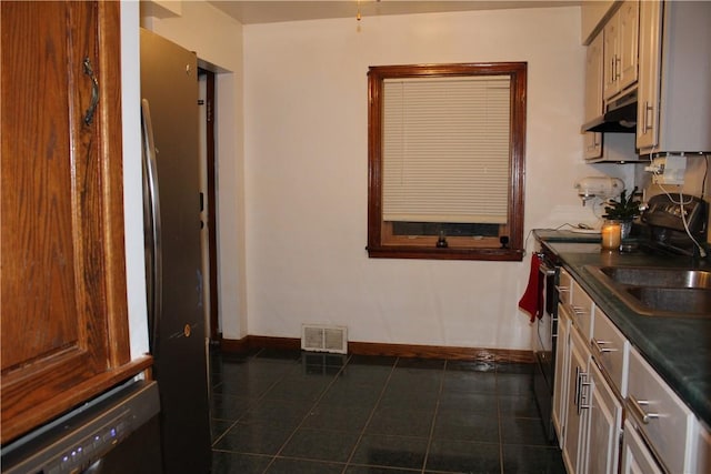 kitchen featuring dark tile patterned floors, extractor fan, and sink