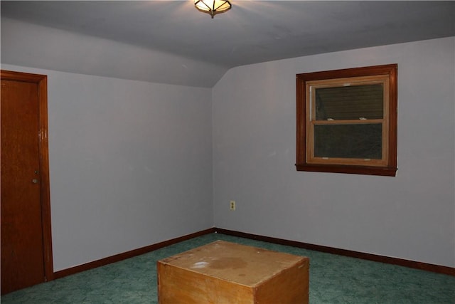 bonus room with dark carpet and lofted ceiling