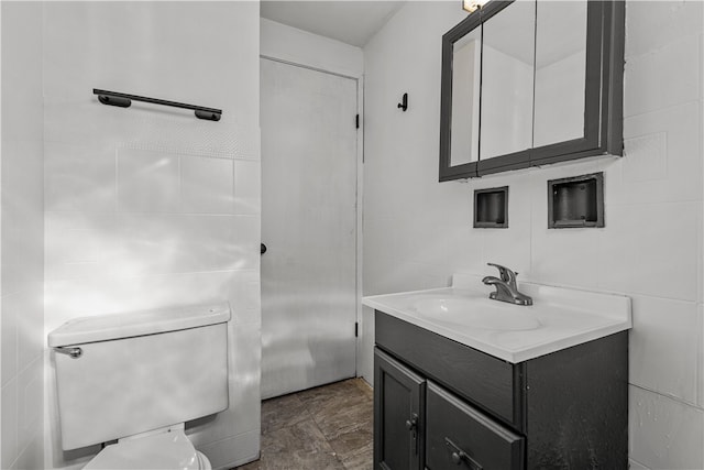 bathroom featuring vanity, toilet, and tile walls