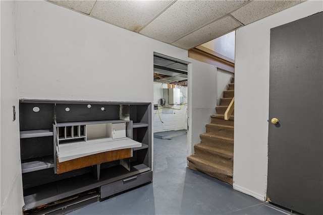 staircase featuring concrete flooring and a drop ceiling