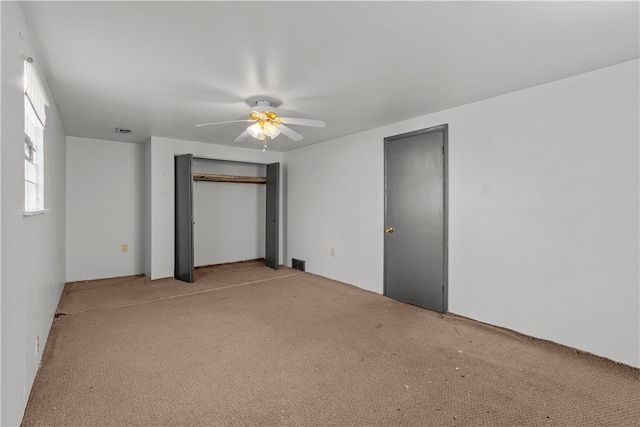 unfurnished bedroom with two closets, light carpet, and ceiling fan