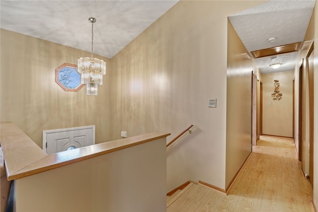 corridor with light hardwood / wood-style flooring and an inviting chandelier