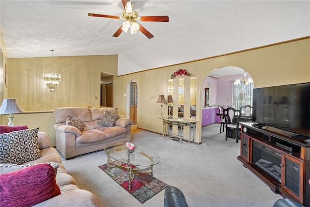 carpeted living room featuring ceiling fan with notable chandelier and vaulted ceiling