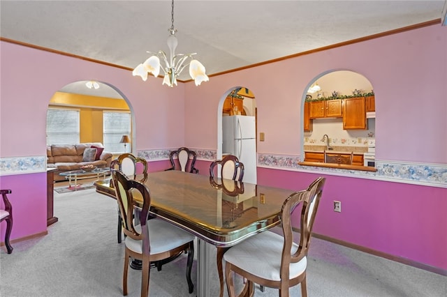 carpeted dining room with crown molding, a notable chandelier, and sink