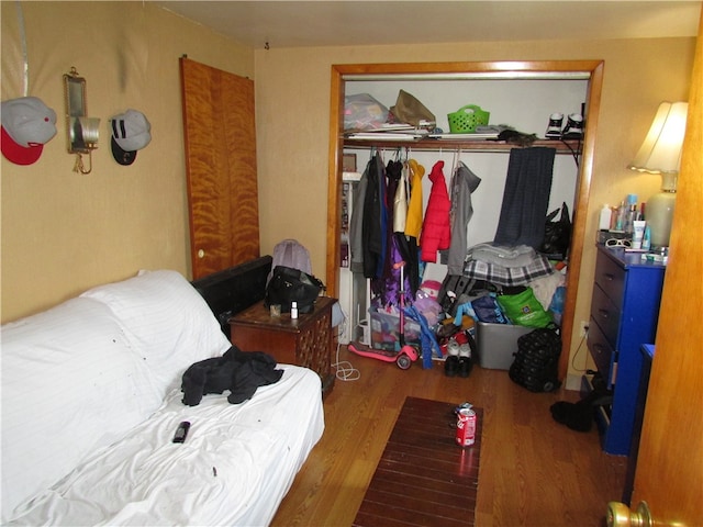 bedroom with dark hardwood / wood-style floors and a closet