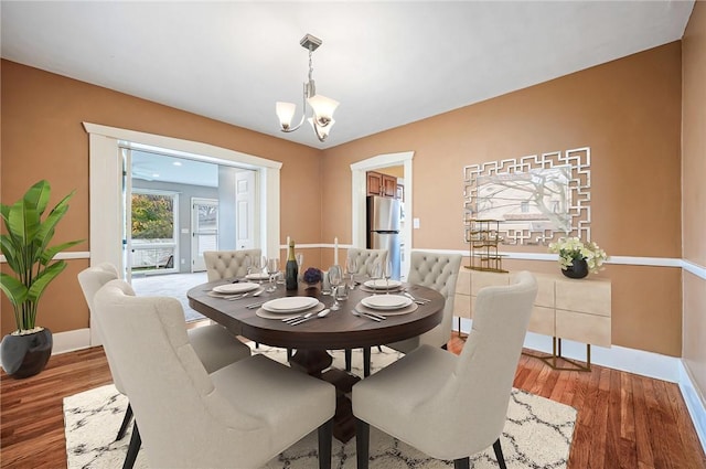 dining space featuring hardwood / wood-style flooring and an inviting chandelier