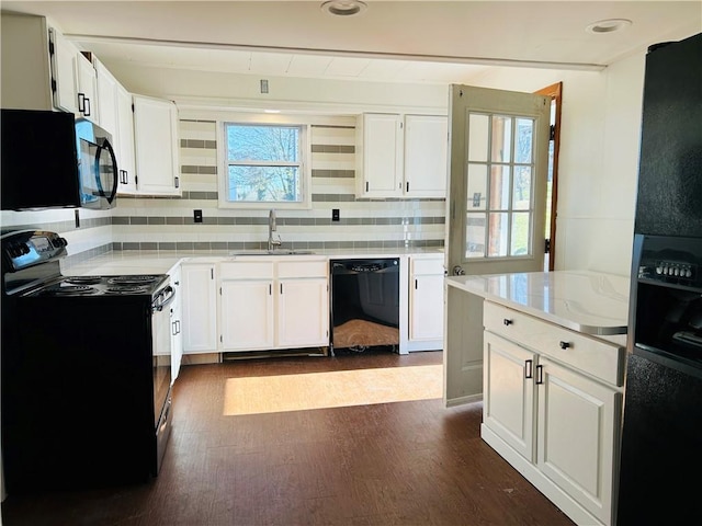 403 Lowell St, Vandergrift, PA 15690 - kitchen featuring black appliances, light countertops, dark wood-type flooring, decorative backsplash, and white cabinets