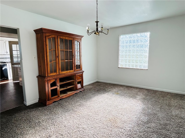 unfurnished dining area featuring dark colored carpet and a chandelier