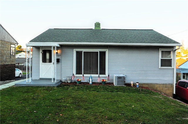 back of house featuring central AC unit and a lawn