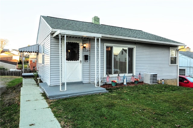 back of house with central AC and a yard