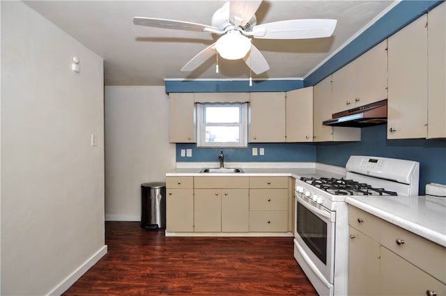 kitchen featuring dark hardwood / wood-style flooring, cream cabinets, white gas range oven, sink, and ceiling fan