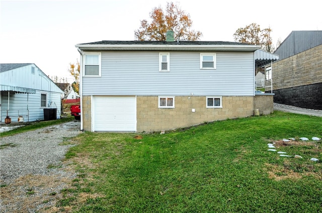 rear view of house featuring a garage and a lawn