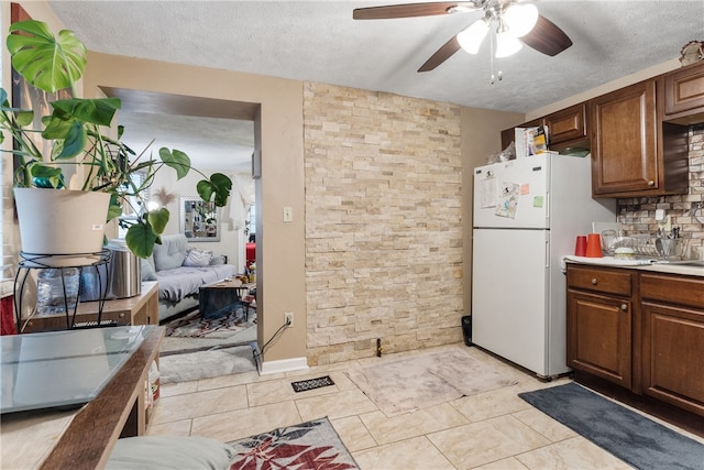 kitchen featuring ceiling fan, a textured ceiling, light tile patterned floors, and white fridge