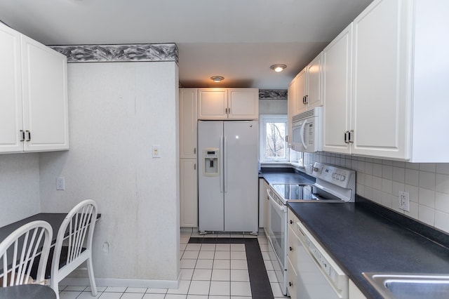 kitchen featuring tasteful backsplash, white appliances, light tile patterned flooring, and white cabinets