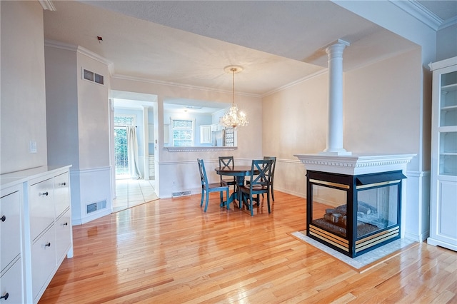 dining area featuring a chandelier, light wood-type flooring, and crown molding