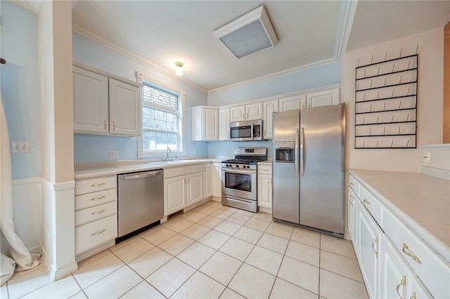 kitchen featuring ornamental molding, stainless steel appliances, sink, light tile patterned floors, and white cabinets