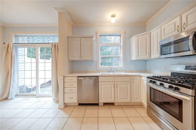 kitchen with appliances with stainless steel finishes, light tile patterned floors, plenty of natural light, and sink