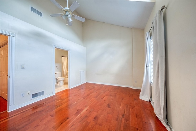 unfurnished bedroom with ceiling fan, ensuite bathroom, vaulted ceiling, and hardwood / wood-style flooring