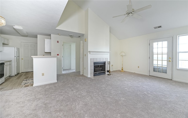 unfurnished living room with a fireplace, light carpet, high vaulted ceiling, and ceiling fan