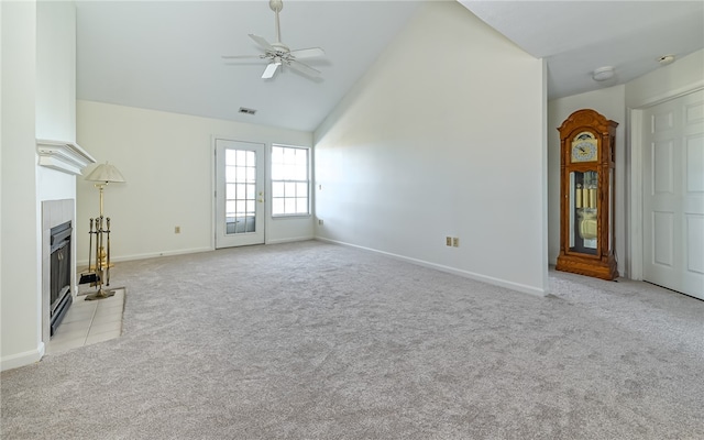 unfurnished living room with high vaulted ceiling, ceiling fan, a tile fireplace, and light carpet