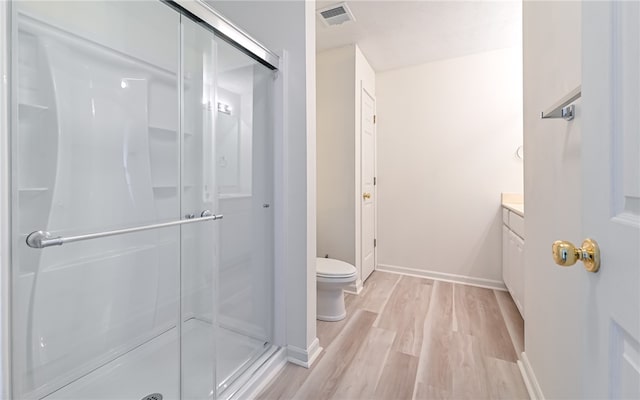 bathroom with wood-type flooring, vanity, toilet, and an enclosed shower