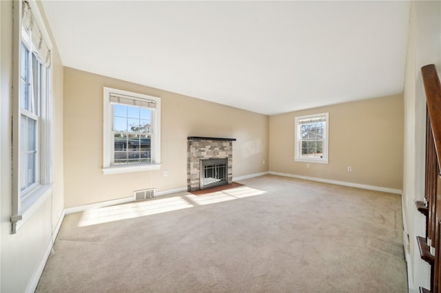 unfurnished living room featuring light carpet and a stone fireplace