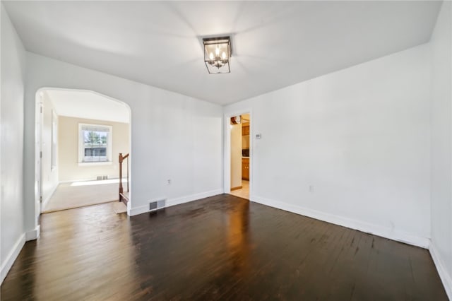 empty room featuring a notable chandelier and dark hardwood / wood-style floors