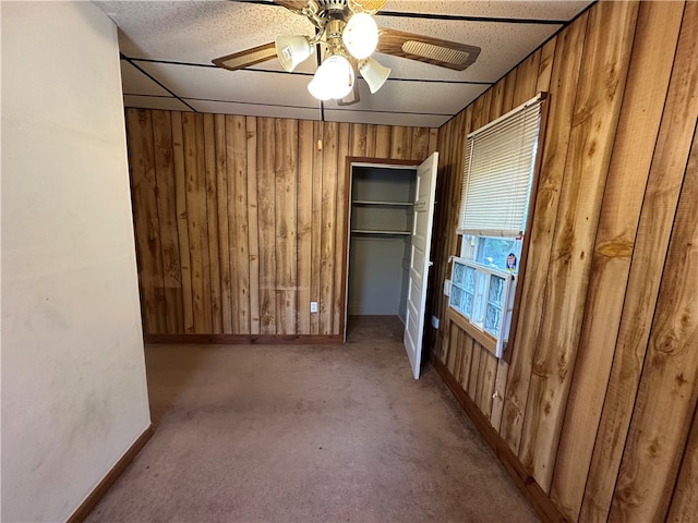 spare room featuring wooden walls, ceiling fan, and light colored carpet