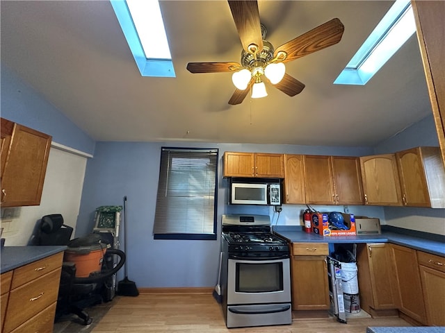 kitchen with vaulted ceiling with skylight, stainless steel appliances, plenty of natural light, and light hardwood / wood-style floors