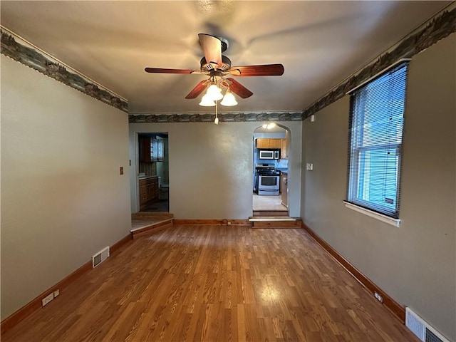 1447 Fleming Ave, Mckees Rocks, PA 15136 - empty room with arched walkways, ceiling fan, baseboards, and wood finished floors