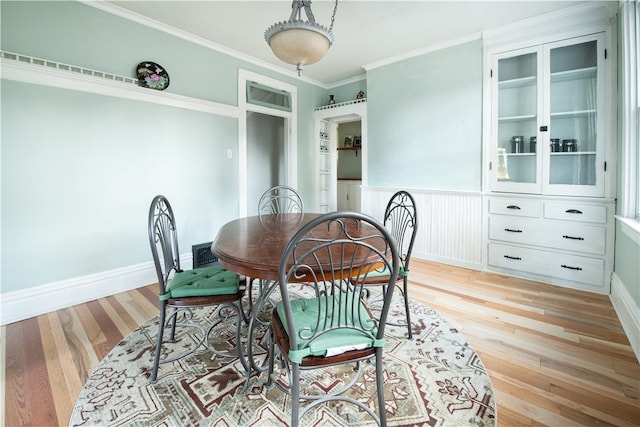 dining space with light hardwood / wood-style floors and crown molding