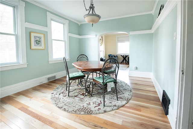 dining area featuring light hardwood / wood-style flooring, ornamental molding, and plenty of natural light