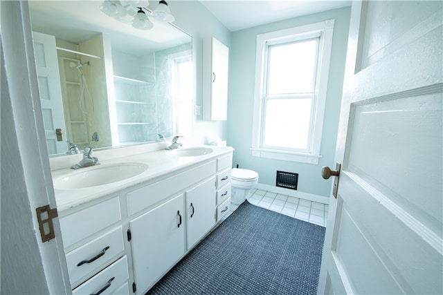 bathroom with tile patterned flooring, vanity, a healthy amount of sunlight, and walk in shower