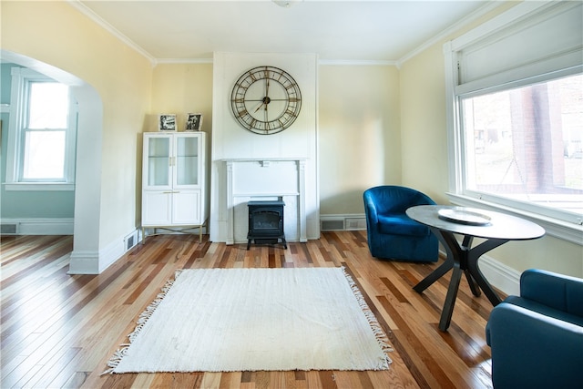 living area featuring a wood stove, ornamental molding, and light wood-type flooring