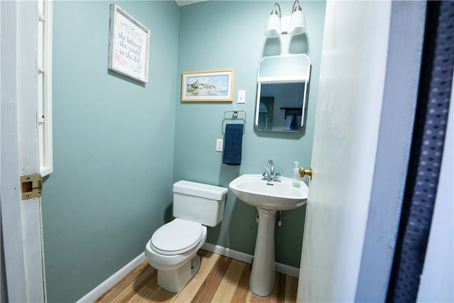 bathroom featuring toilet, sink, and wood-type flooring