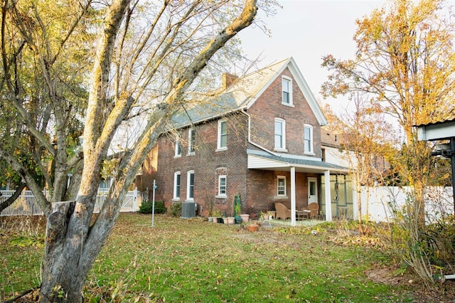 view of front of home with central air condition unit, a front yard, and a patio