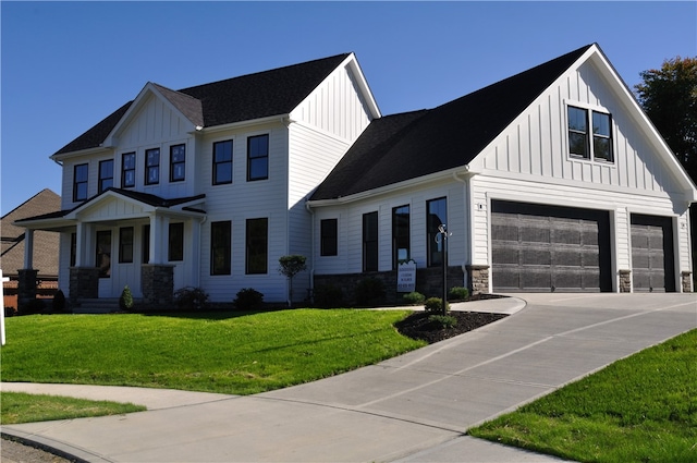 view of front facade with a garage, stone siding, concrete driveway, board and batten siding, and a front yard