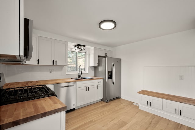 kitchen featuring wood counters, sink, light hardwood / wood-style floors, white cabinetry, and stainless steel appliances