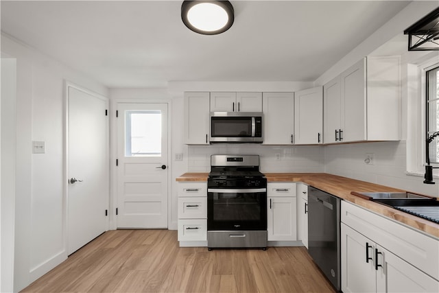 kitchen with butcher block countertops, light hardwood / wood-style floors, white cabinetry, and appliances with stainless steel finishes