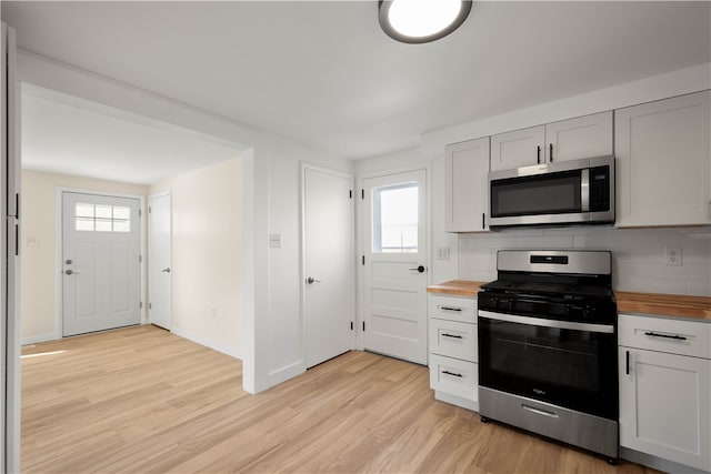 kitchen with backsplash, butcher block counters, a healthy amount of sunlight, and stainless steel appliances