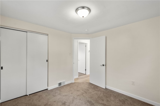 unfurnished bedroom featuring a closet and light colored carpet