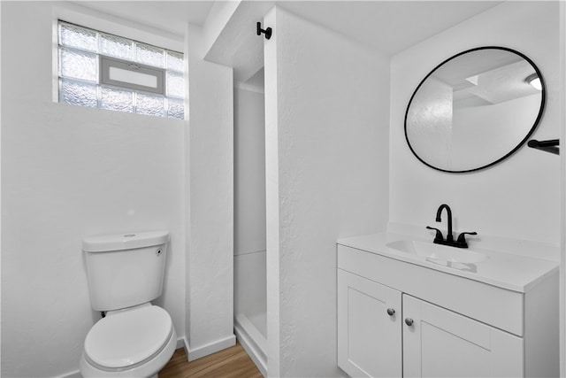 bathroom featuring walk in shower, hardwood / wood-style floors, vanity, and toilet