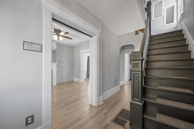 staircase featuring ceiling fan and hardwood / wood-style floors