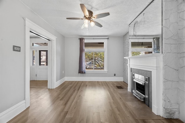 unfurnished living room with ceiling fan, a textured ceiling, and hardwood / wood-style flooring