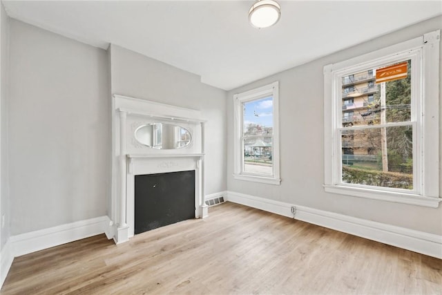 unfurnished living room featuring light wood-type flooring and plenty of natural light