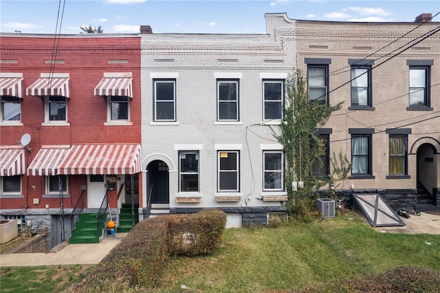 view of front of property with a front lawn and central AC unit