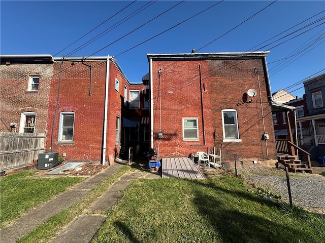 back of house with central air condition unit and a yard